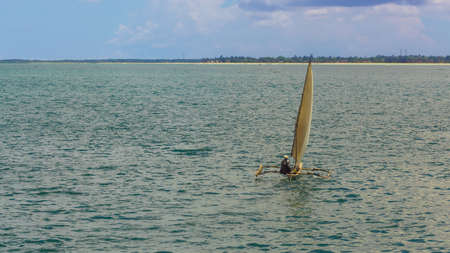 A man sailing on a small handmade sailboat in the middle of the Indian Oceanの写真素材