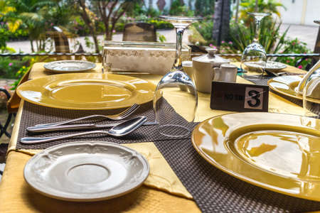 A table setup at a restaurant with plates, glasses and cutlery by the sideの写真素材