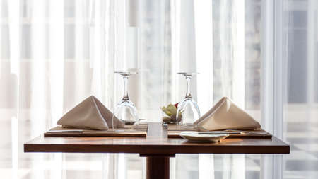 A simple and beautifully arranged table for two, with cloth napkins and wine glassesの写真素材