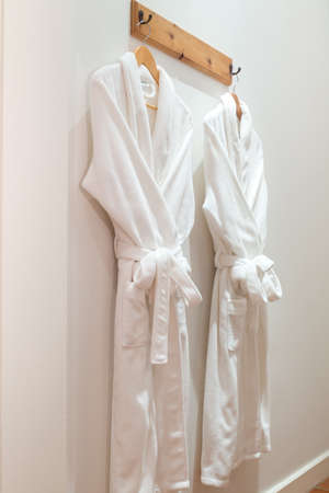 Two bathrobes hanging on hooks mounted on the wallのeditorial素材