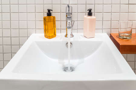 White porcelain hand wash basin with liquid soap and hand lotionのeditorial素材