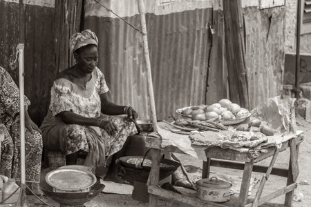 Mbour, Senegal - July, 2014: A woman selling food on the street roasts peanuts in a wok on July 9,...