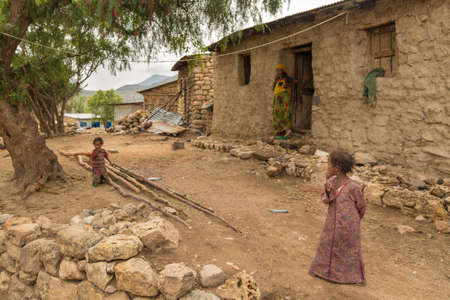 Two little girls play just outside of their homes with their mother watching in the rural regions of Harar, Ethiopia on July 26, 2014のeditorial素材