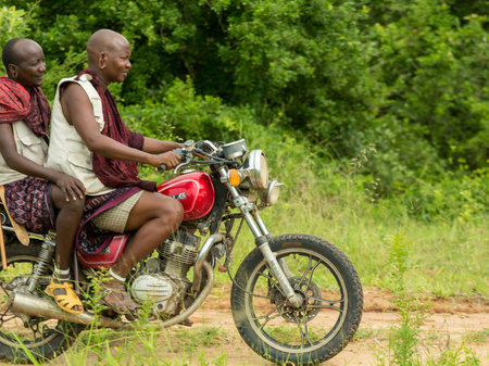Morogoro, Tanzania: April 23: Two members of the Maasai tribe dressed in their distinct traditional clothing and riding a motorcycle - April 23, 2015 in Morogoro, Tanzaniaのeditorial素材