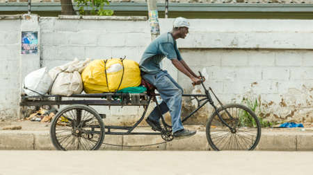 Dar Es Salaam: April 22: A man rides his customised bicycle fitted with a trailer that is loaded with large sacs, on April 22, 2015 in Dar Es Salaam, Tanzaniaのeditorial素材