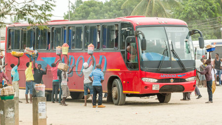 Dar Es Salaam: April 22: Street vendors surround a bus with merchandise to sell to its passengers, as it departs from the bus station, on April 22, 2015 in Dar Es Salaam, Tanzaniaのeditorial素材