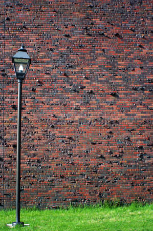 a red brick wall with a lamp and green grassの写真素材
