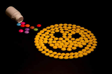Yellow smiley emoticon made from candy, danger of drugs, drugs looking like candy conceptの写真素材