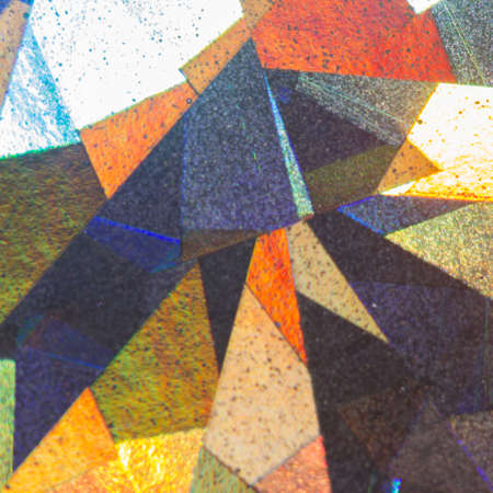 Colorful geometric patterns formed by light reflecting off a textured metallic surfaceの写真素材