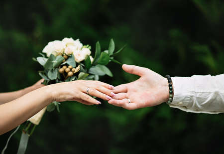 Hands with wedding rings and bouquet. green backgroundの写真素材