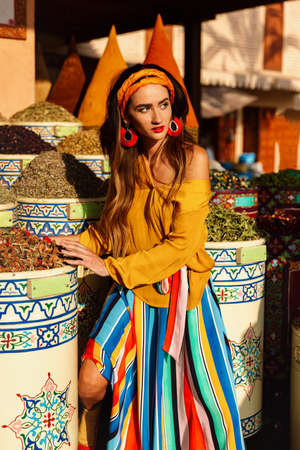 A beautiful girl stands near spices in the market of the city of Essaouira in Moroccoの写真素材