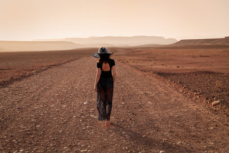 A girl in a hat walks along a road near the city of Ouarzazate. Moroccoの写真素材