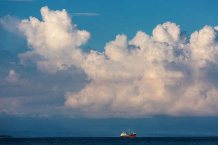 A ship on the background of a blue sky with big white clouds.の写真素材