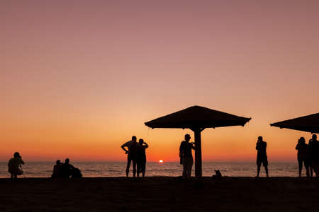 Silhouettes of people at sunset. People meet the sunset.の写真素材
