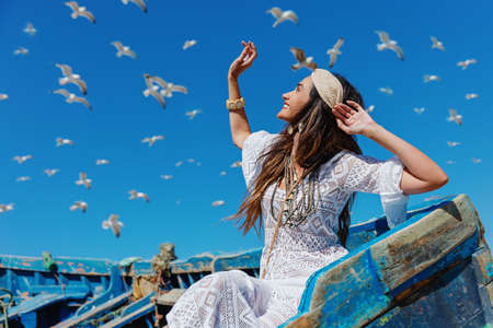 Happy girl looks at the sky and flying seagulls. Essaouira. Moroccoの写真素材