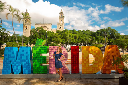 Downtown Merida in Mexico. A tourist girl stands near the capital letters - of the name of the city...