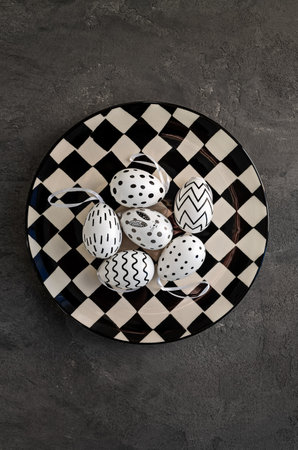 Black and white plate with colored eggs on a concrete background. Easter card, background.の写真素材