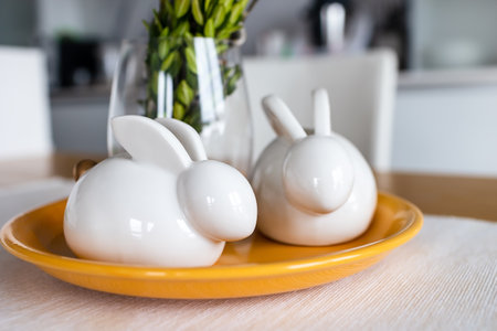 Two ceramic Easter bunnies on a yellow plate .Easter backgroundの写真素材
