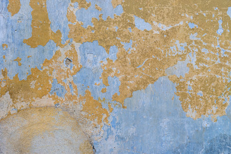 The texture of old, cracked, peeling walls. The background is blue and yellow wallsの写真素材