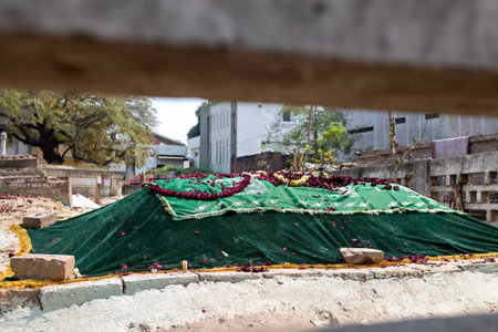 The grave is covered with a green cloth, and there is a wreath of flowers on it. Varanasi, Indiaの写真素材