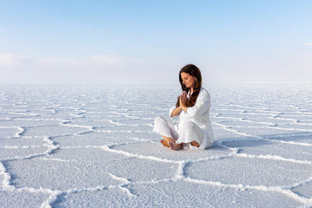 A woman in a white dress is meditating. Salar de Uyuni. Bolivia.の写真素材