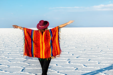 A girl in a hat and poncho looks at the Salar de Uyuni, Bolivia.の写真素材