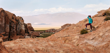 A girl in a hat with a backpack is in the valley of stones. Bolivia. Altiplano. Uyuni. Panorama