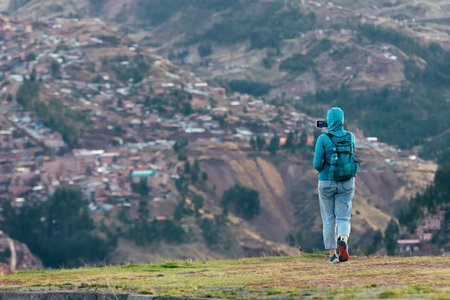 A tourist girl takes pictures of the city of Cusco from an observation deck. Peruの写真素材