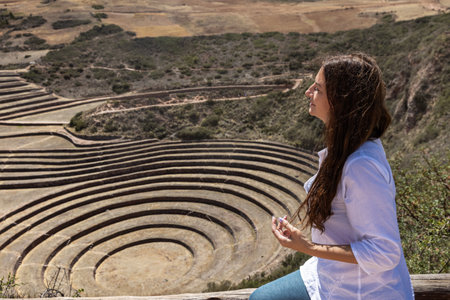 A female tourist with long dark hair looks at the circular terraces in Moray, Peru.の写真素材