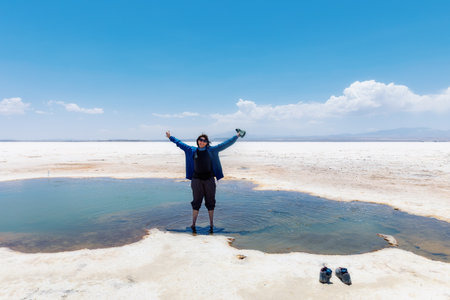 Happy woman with raised arms standing in the water of Lake Uyuni, Bolivia.の写真素材