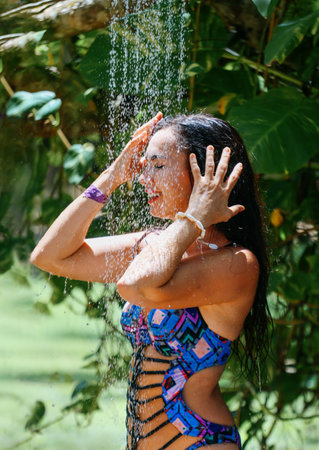 A happy girl in a swimsuit is taking a shower outside. Exotic Vacationの写真素材