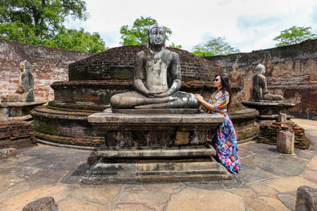 Woman visits a statue of Buddha in an ancient temple in Sri Lanka. Polonnaruwaの写真素材