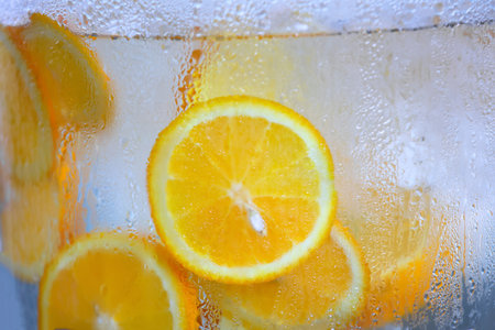 Refreshing orange slices in chilled water in a glass jar. Cooling drink. Selective focusの写真素材