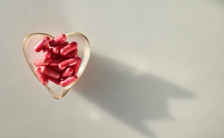 Heart-shaped dish filled with pink capsules. Space for text