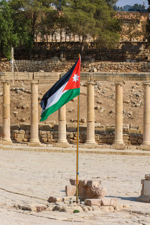Jordanian Flag Waving Proudly Amidst the Ancient Roman Ruins of Jerashの写真素材