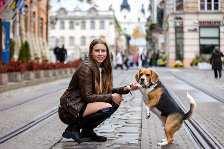 Young Woman and Her Beagle Dog Sharing a Playful Moment on a City Streetの写真素材