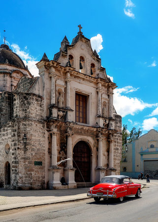Classic red car parked in front of a historic colonial building in Havanaの写真素材