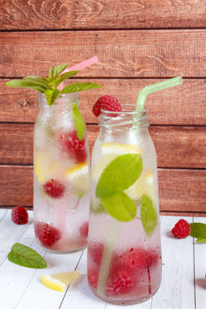Cold cocktail with raspberries, lemon and mint. Wooden background.の写真素材