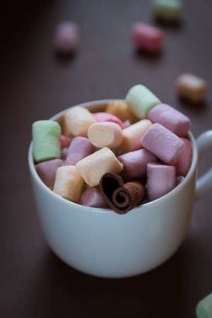 Hot chocolate in a white Cup with colored marshmallows on a dark background. Selective focusの写真素材