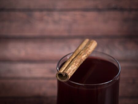 Glass Cup of red wine mulled wine on a wooden background with cinnamon backgroundの写真素材