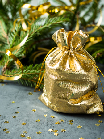 Fir branches on the grey concrete background with gold stars. New Year Christmas. Golden bag with gifts.の写真素材