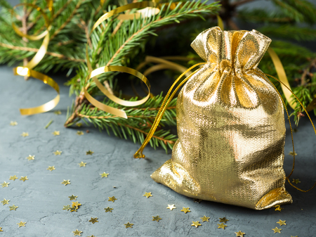 Fir branches on the grey concrete background with gold stars. New Year Christmas. Golden bag with gifts.の写真素材