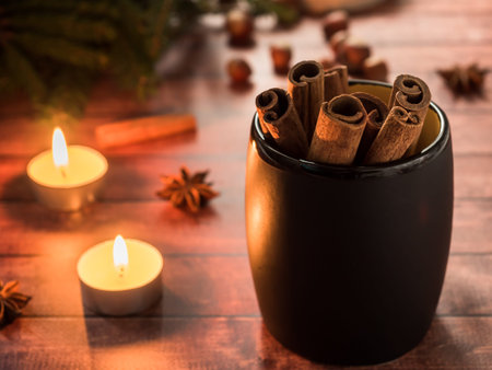 Black ceramic Cup with cinnamon on dark wooden table with candles.の写真素材