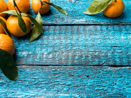 Fresh Mandarin or tangerine with stems and leaves on blue wooden background copy space.の写真素材