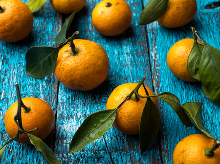 Fresh Mandarin or tangerine with stems and leaves on blue wooden background flat lay.の写真素材