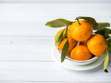 Fresh mandarin or tangerines with stems and leaves on white wooden background Copy spaceの写真素材