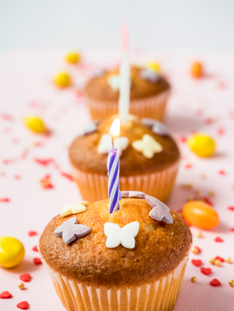 Birthday cupcakes with candles on the table. Pink backgroundの写真素材