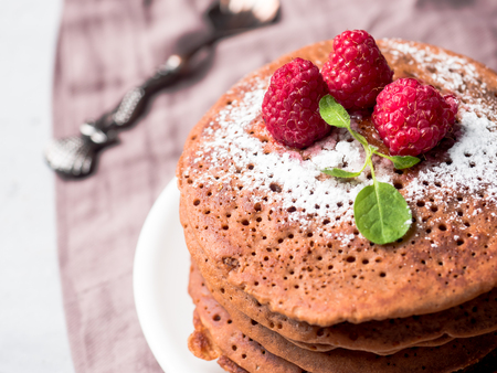 Chocolate pancakes with powdered sugar raspberry on light backgroundの写真素材