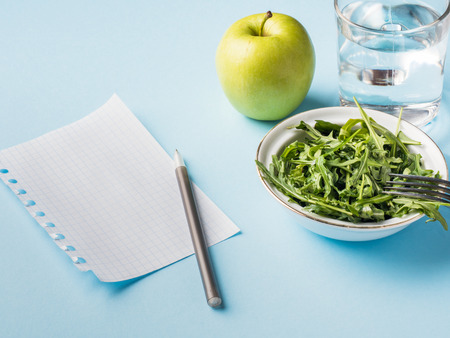 Diet leaves salad green Apple a glass of water on blue background.の写真素材