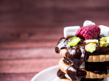 A sweet dessert of chocolate biscuit, raspberry marshmallow and a Cup of coffee on dark backgroundの写真素材